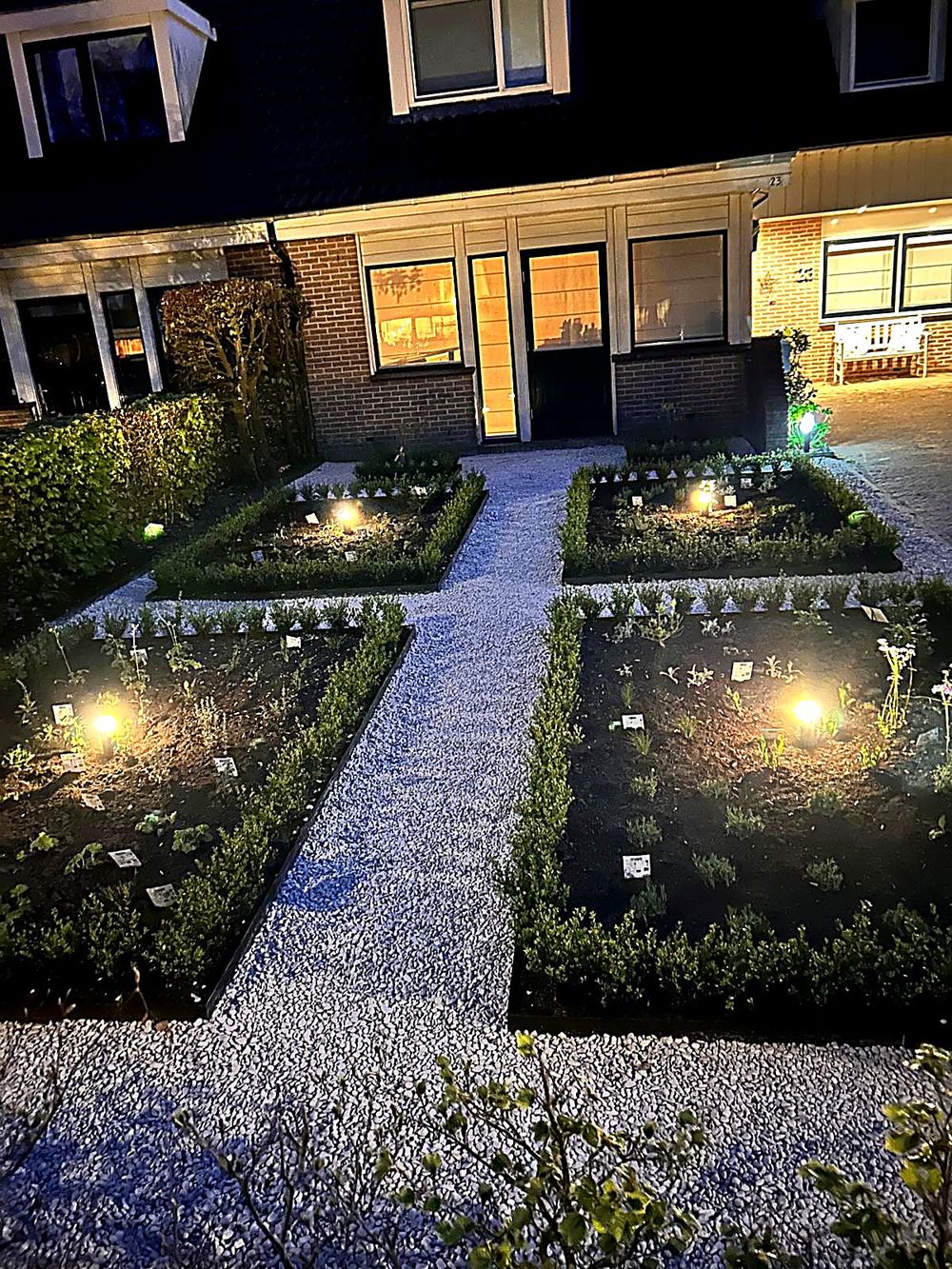 Verlichte border met buxushagen bij avond, aangelegd door Roks Tuinen